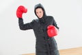 Tought woman in hooded jacket and red boxing gloves