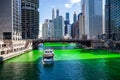 Tour boat crosses a dyed green Chicago River, which is surrounded by crowds