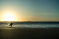 Tourinhos, Brazil, November 23, 2022. Silhouette of a surfer running into the waves with his board during sunset. In the Royalty Free Stock Photo
