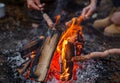 Cropped of hikers frying sausages on sticks while camping