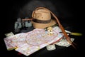 Tourism and adventure concept. Compass on city map with flashlight, fedora hat, bullwhip, binocular, knife and dollar bills on dar Royalty Free Stock Photo