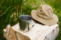 Tourism day. tin mug and hat with wide brim sun protective lie on a log in the forest Royalty Free Stock Photo