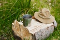 Tourism day. metal mug and tourist hat with fields lie on a log in the forest Royalty Free Stock Photo