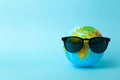 Tourism, ecology, vacation and globalism concept. Globe in sunglasses on a blue background banner. Minimal creative