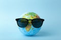 Tourism, ecology, vacation and globalism concept. Globe in sunglasses on a blue background banner. Minimal creative