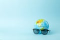 Tourism, ecology, vacation and globalism concept. Globe in sunglasses on a blue background banner. Minimal creative