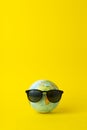Tourism, ecology, vacation and globalism concept. Globe in sunglasses on a yellow background. Minimal creative