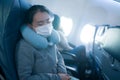 Tourism and flying in times of covid19 - young sweet and tired Asian Chinese woman in face mask sitting on airplane cabin sleeping
