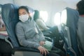 Tourism and flying in times of covid19 - young sweet and tired Asian Japanese woman in face mask sitting on airplane cabin