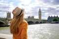 Tourism in London. Back view of traveler girl enjoying sight of Westminster bridge and palace on River Thames with famous Big Ben Royalty Free Stock Photo