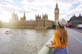 Tourism in London. Back view of traveler girl enjoying sight of Westminster palace and bridge on Thames with famous Big Ben tower Royalty Free Stock Photo