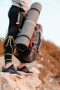 Tourism and sports recreation. A woman holds a tourist backpack and a Mat. Close-up of legs and sports equipment. Vertical Royalty Free Stock Photo