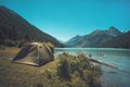 Tourism and traveling concept. Beautiful summer landscape with mountains and tourist tent. green tent stands near the lake in the