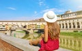 Tourism in Tuscany. Rear view of young fashion woman sitting and looking at Ponte Vecchio bridge in Florence, Italy Royalty Free Stock Photo