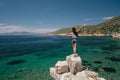 The tourist admires the sea view. The girl is on vacation. A woman stands on the edge of a cliff and is very happy.