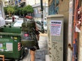 A tourist and Airbnb user walking past an anti-Airbnb posted in the Koukaki area of Athens, Greece.