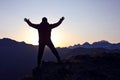 Tourist with arms raised standing on the mountain at dawn