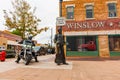 Tourist arrives on Harley Davidson motorcycle at famous Winslow Arizona br statue of Eagles ban-member Glenn Frey under sign