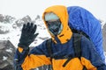 A tourist with a backpack in the mountains in severe bad weather wearing a west-protective mask and glasses Royalty Free Stock Photo