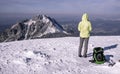 Tourist with backpack and poles looking on winter mountains