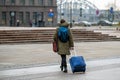 A tourist with a backpack pulls a suitcase on wheels down the street, rear view, Riga, Latvia Royalty Free Stock Photo