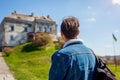 Tourist backpacker visiting Olesko Castle in spring. Trip to Western Ukraine. Traveler man enjoys architecture