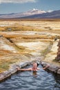 Tourist bathing in hot springs, Sajama national park, with volcano Parinacota in the background, Bolivia