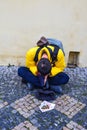 A tourist beggar sitting on a stone pavement