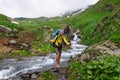 The tourist with a big backpack crossing river ford.