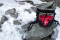 Tourist black backpack lying at snow and stone