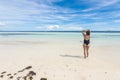 A tourist in a black one piece swimsuit unwinds at a pristine white sand beach. Dumaluan Beach in Panglao Island, Bohol,