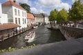 Tourist boat in bruges canal near old bridge on sunny summer day