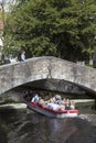 Tourist boat in bruges canal under old bridge on sunny summer da