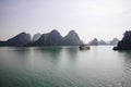 Tourist boat cruising through Ha Long bay under a misty sky in Quang Ninh, Vietnam Royalty Free Stock Photo