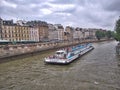 Tourist boat operated by Bateaux-Mouches with tourists onboard looking at the scenery, on the Seine River in Paris, France.