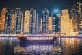 Tourist Boat, Sightseeing Boat Sailing On Dubai Marina At Nighttime. Night View Of high-rise buildings of residential Royalty Free Stock Photo