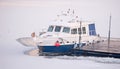 Tourist boat tied to the wooden dock on frozen river during cold Royalty Free Stock Photo