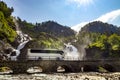 Tourist bus traveling on the road Latefossen Waterfall Odda Norway. Latefoss is a powerful, twin waterfall