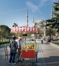 Tourist buying fast food meal from a traditional Turkish Simit Turkish Bagel cart in Sultan Ahmed Square, Istanbul, Turkey