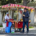 Tourist buying food from a traditional Turkish chestnut and corn cart in Sultan Ahmed Square, Istanbul, Turkey