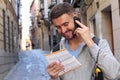 Tourist calling by phone while looking at tourism guide or dictionary Royalty Free Stock Photo