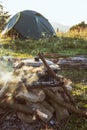 Tourist camp with fire, pot, tent and firewood Royalty Free Stock Photo