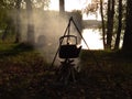 Tourist camping kettle on the fire boils on the background of the forest and the river