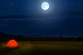Tourist camping near forest in the night. Illuminated tent under beautiful night sky full of stars and full moon. Hiking in Royalty Free Stock Photo
