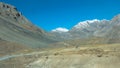 A Tourist car driving far away long mountain hill road trip. Leading to distant peaks Snow covered Desert Himalayas. Mount Everest Royalty Free Stock Photo