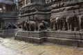 Tourist at Cave 16 with huge beasts carved around the shrine`s high plinth or platform including elephants, leonine and other best