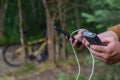 A tourist charges a smartphone with a power bank on the background of a bicycle in forest