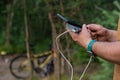 A tourist charges a smartphone with a power bank on the background of a bicycle in forest