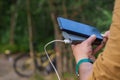 A tourist charges a smartphone with a power bank on the background of a bicycle in forest