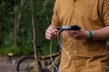 A tourist charges a smartphone with a power bank on the background of a bicycle in forest